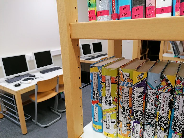 ein Bücherregal mit Computern im Hintergrund