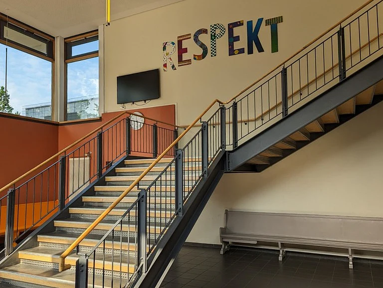 Die Treppe im Foyer der Schule mit einem großen Wandbild mit dem Titel Respekt