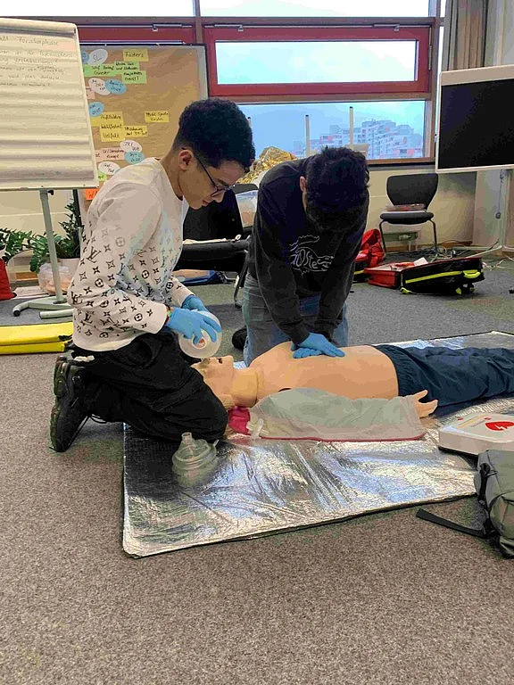 Ein Schüler, der vor einem Torso sitzt, mit dem man Beatmen üben kann. 